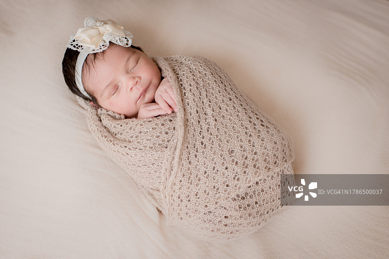 新生儿照片：睡在米色毯子里的女婴图片素材