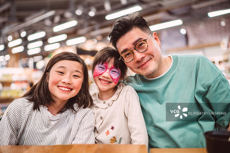 父亲和女儿在餐厅聚会时对着镜头开心地微笑图片素材