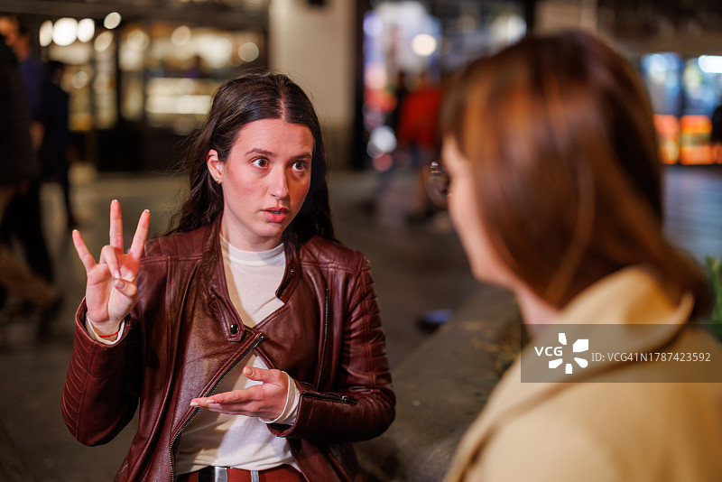 星空下长椅上用手语交谈的两个朋友图片素材