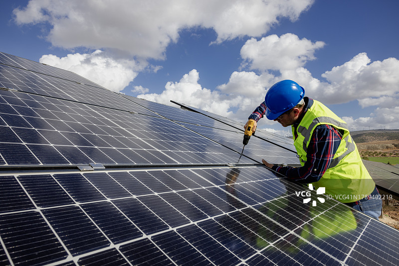 使用钻头安装太阳能电池板的安装工人图片素材