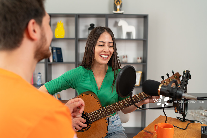 女人一边弹吉他唱歌，一边录制视频博客或视频日志图片素材