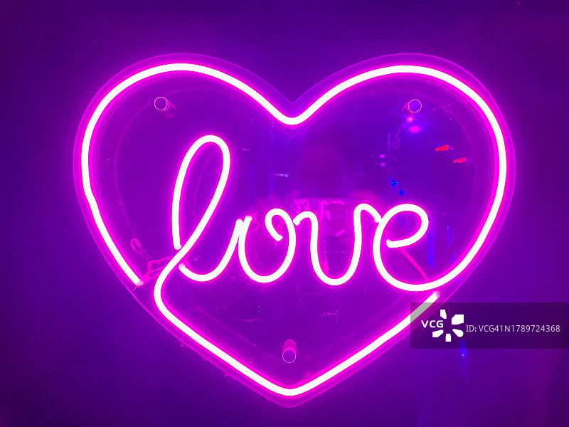 黑色墙壁上的心形粉色霓虹灯图片素材