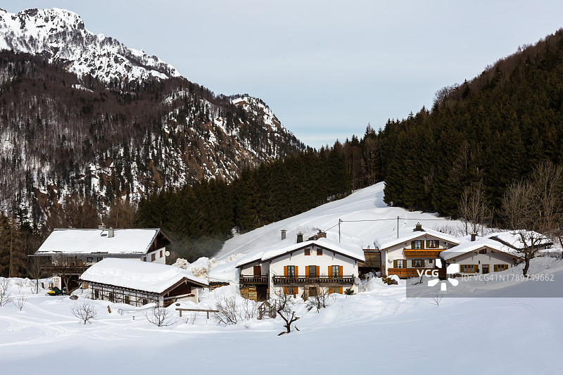 白雪皑皑的山脉中拥有巴伐利亚传统房屋的小村庄图片素材