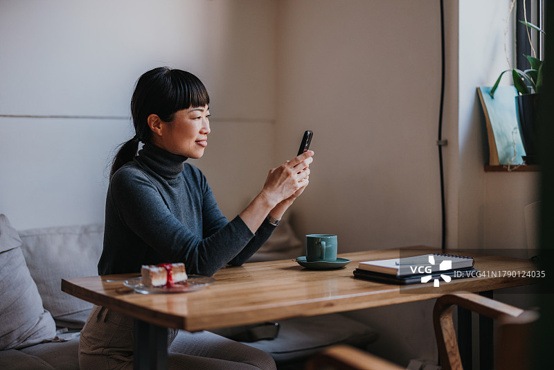 在咖啡店使用手机的漂亮微笑日本女性肖像图片素材
