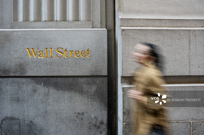 女商人走过华尔街的一栋建筑，华尔街标志，动态模糊图片素材