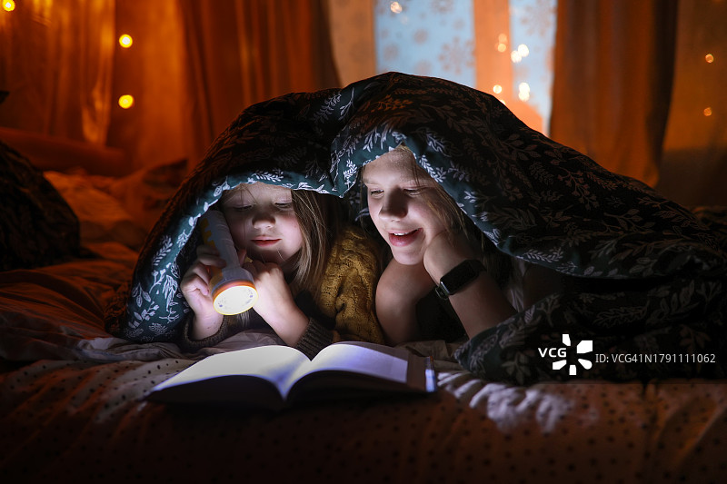 光影瞬间：孩子们用手电筒在夜晚阅读探险图片素材
