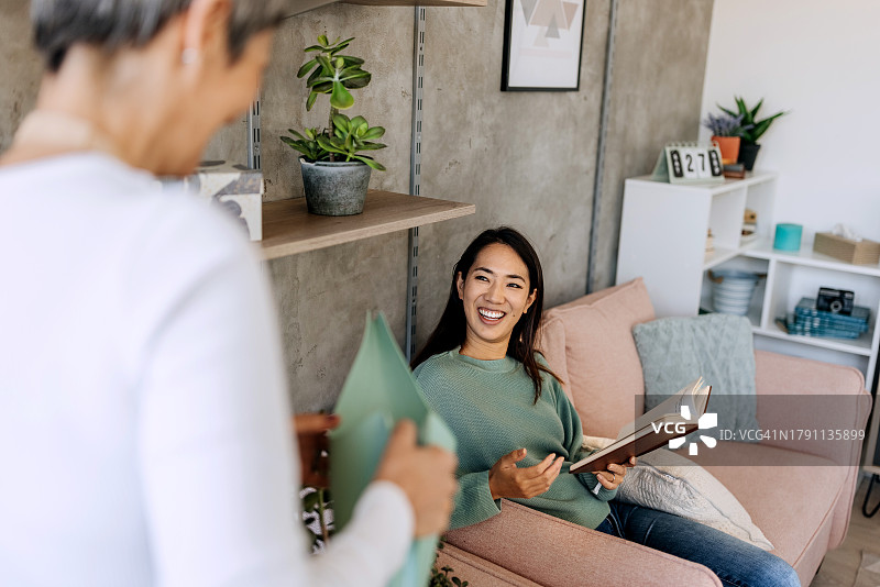 专业女性客房服务员在与业主交谈时给植物浇水图片素材