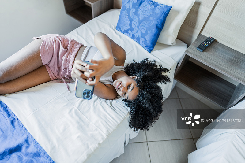 女孩在酒店房间用手机自拍或拍摄图片素材