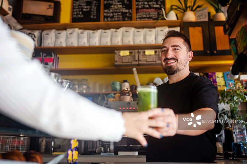快乐的咖啡师为顾客提供抹茶苏打鸡尾酒图片素材