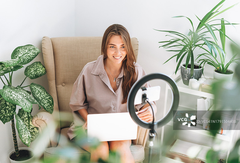 年轻女博主在房间用手机和环形灯录制视频图片素材