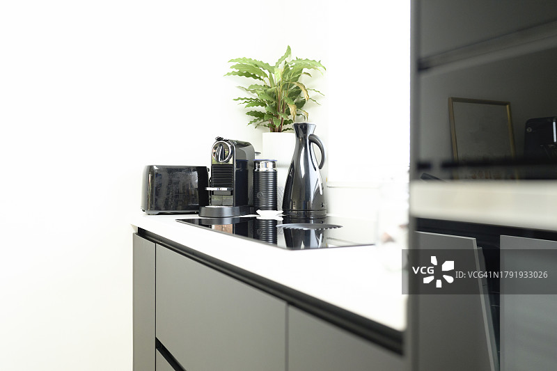 厨房橱柜中咖啡机、烤面包机和水壶的侧面，旁边是冰箱图片素材