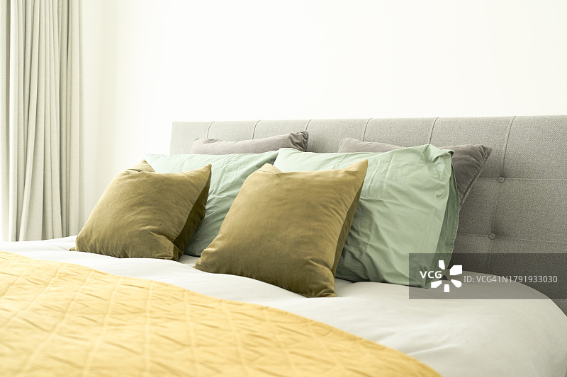 配有绿色枕头、黄色毯子的整洁大床图片素材