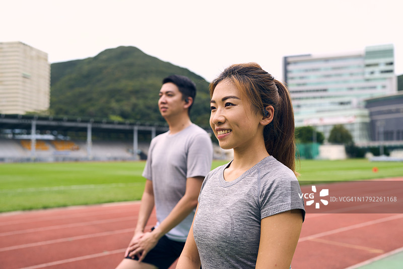 中国夫妇在运动场上做腿部伸展运动图片素材
