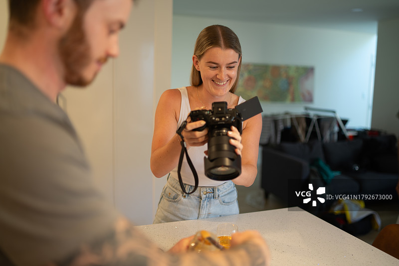 年轻女子拍摄男性烹饪图片素材