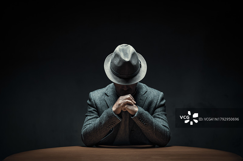 坐在黑暗房间桌子旁的神秘男人图片素材