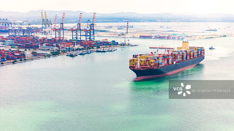 满载集装箱货轮在拖船的协助下靠港，在海港进行装卸作业，国际货轮运输图片素材