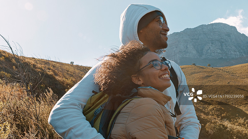 夫妻徒步旅行，在山间拥抱，面带微笑，背着背包站立，亲近大自然。在小路、田野中进行户外旅行、探险和徒步旅行，并通过锻炼保持健康图片素材