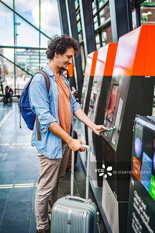 男乘客在车站的自助售票机上购票图片素材