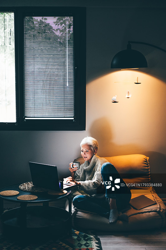 中年妇女在家使用笔记本电脑工作、进行视频通话或浏览互联网图片素材