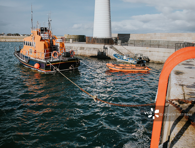 停泊在灯塔旁的港口中的救援救生艇图片素材