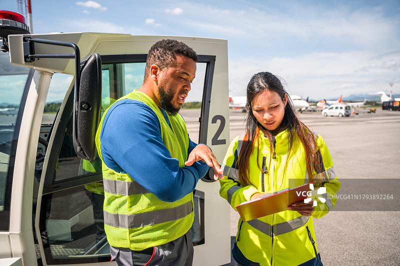 机场工作人员站在跑道上的牵引车前图片素材