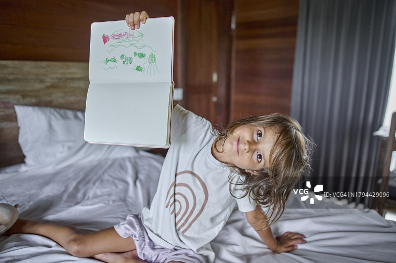 在家中床上拿着素描本的女孩肖像图片素材