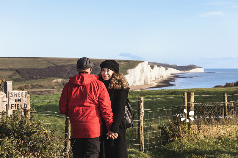 走向英国东萨塞克斯七姐妹海岸救生员小屋的新婚夫妇图片素材