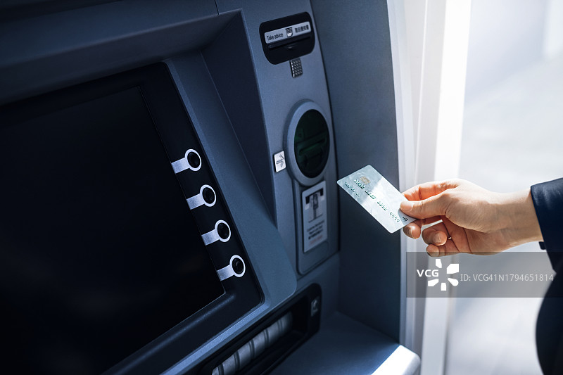 女商人将银行卡插入城市街道上的自动取款机。取款、支付账单、查询账户余额和进行银行转账。隐私保护、移动银行安全概念、随时随地的智能银行图片素材