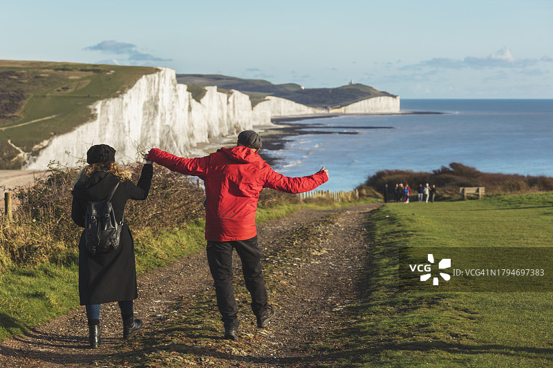走向英国东萨塞克斯七姐妹海岸救生员小屋的新婚夫妇图片素材