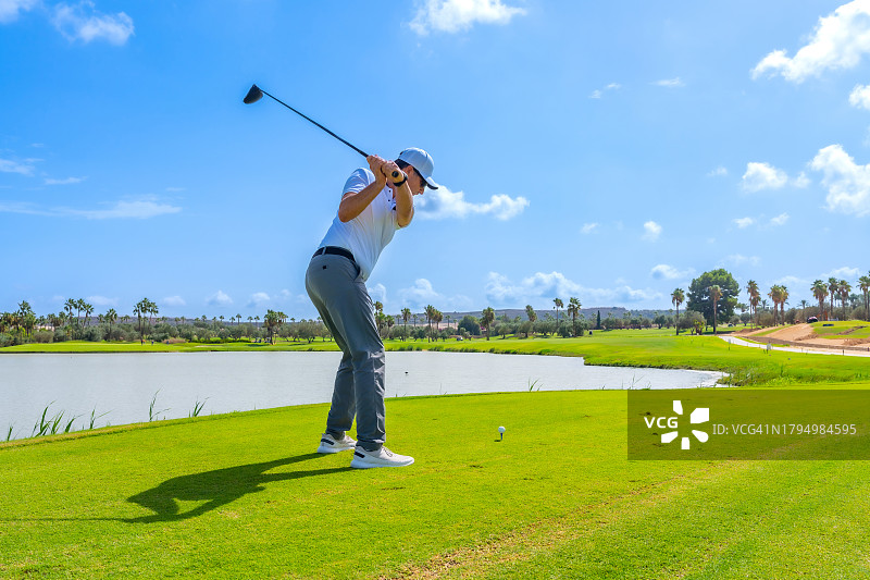 高尔夫球手在绿色球场湖边挥杆图片素材