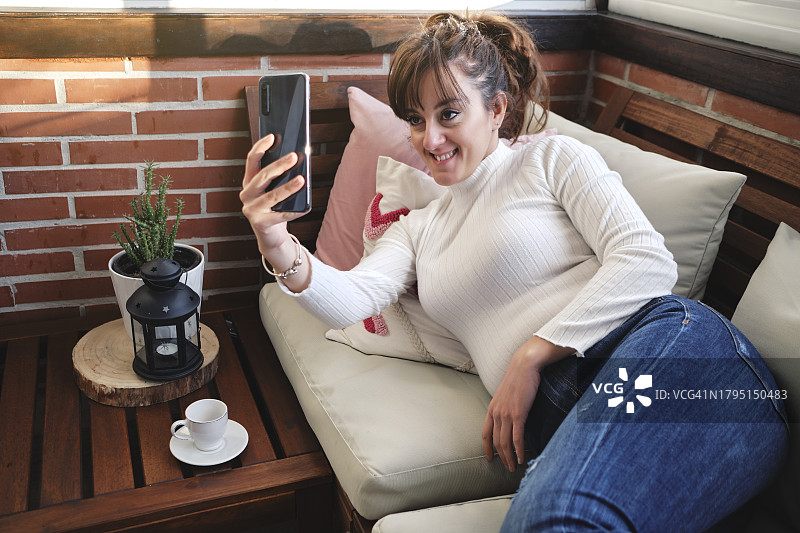 在沙发上进行视频通话的女人图片素材