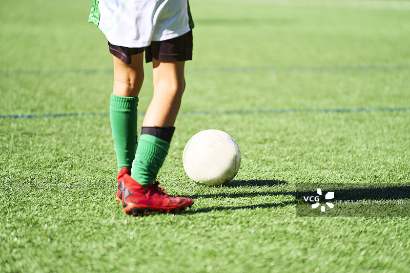 穿着制服的男孩站在足球场草地上图片素材