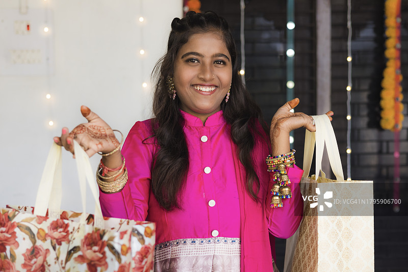 年轻女士穿着传统服装，拿着购物袋和礼物图片素材