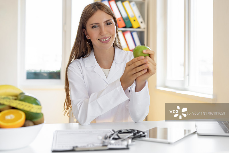 手拿苹果的健康女性营养师图片素材