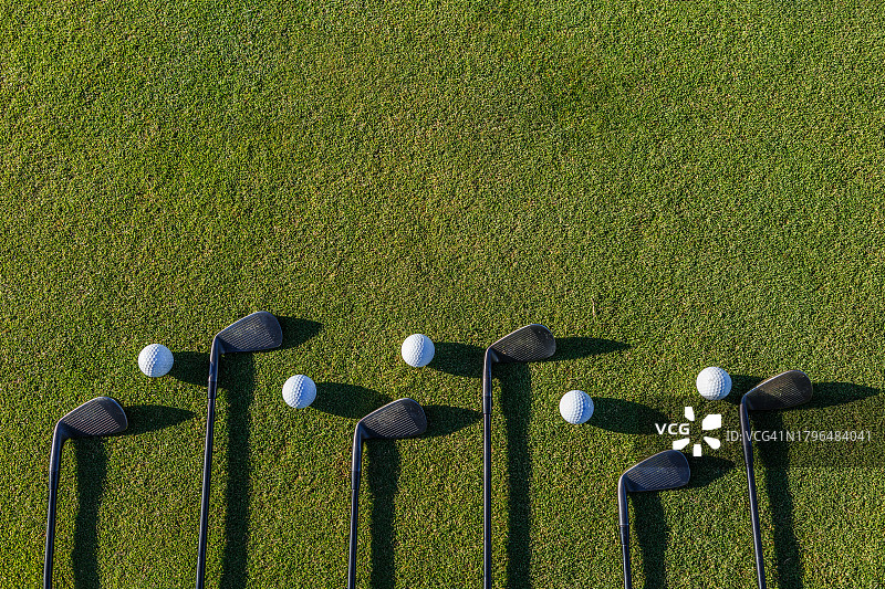绿色地板上的高尔夫球杆和球图片素材
