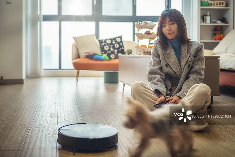 亚洲女人控制智能扫地机器人图片素材