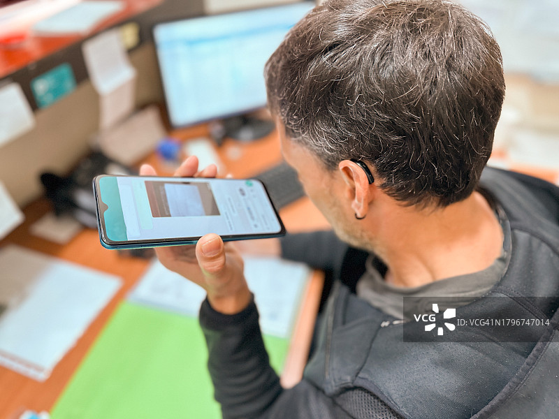 戴着助听器的失聪男人用手机听语音邮件图片素材