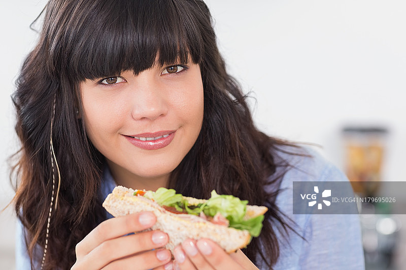 快乐的棕发女子享用沙拉三明治图片素材