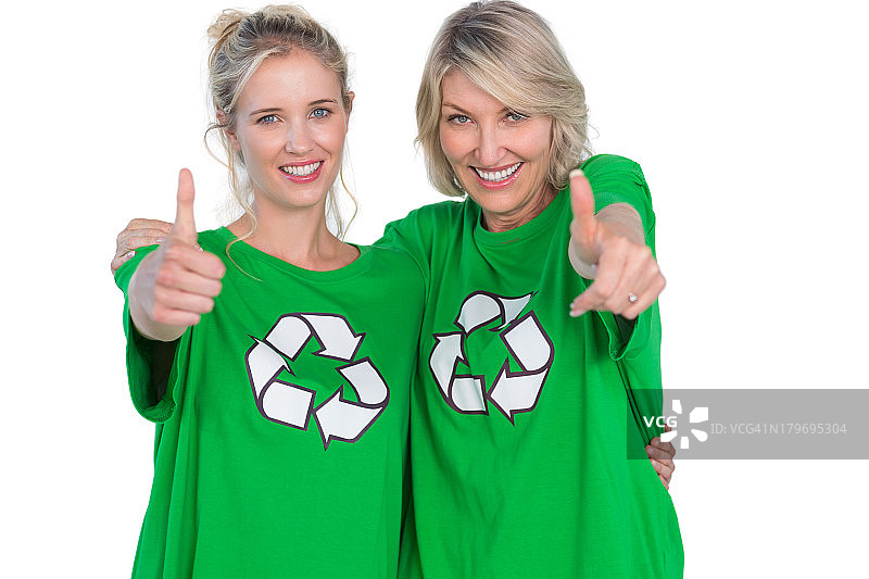 两个穿着绿色回收T恤并竖起大拇指的微笑女性图片素材
