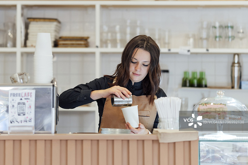 在咖啡店为顾客准备咖啡的年轻女子图片素材