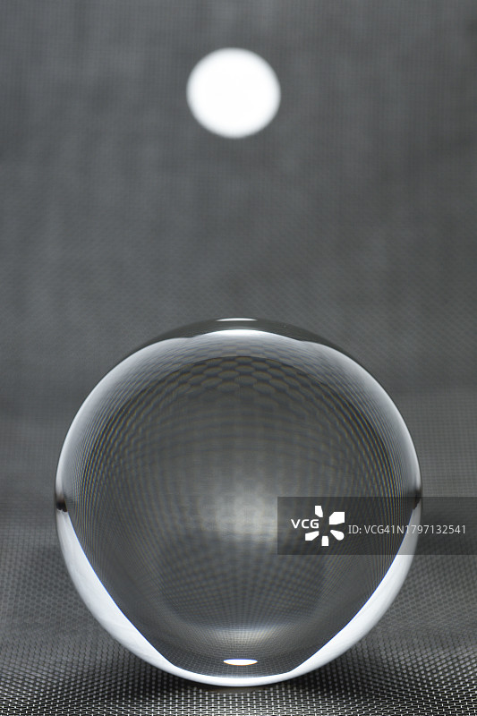 聚光灯背景下金属网上发光的水晶球图片素材
