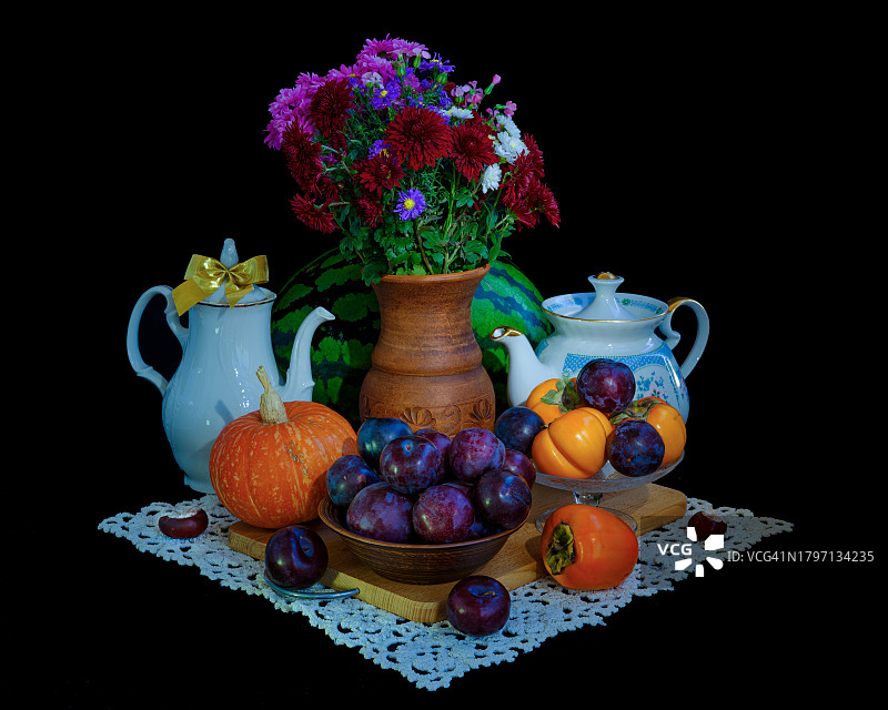 黑色背景下，桌子上带有饮品的水果和鲜花特写图片素材