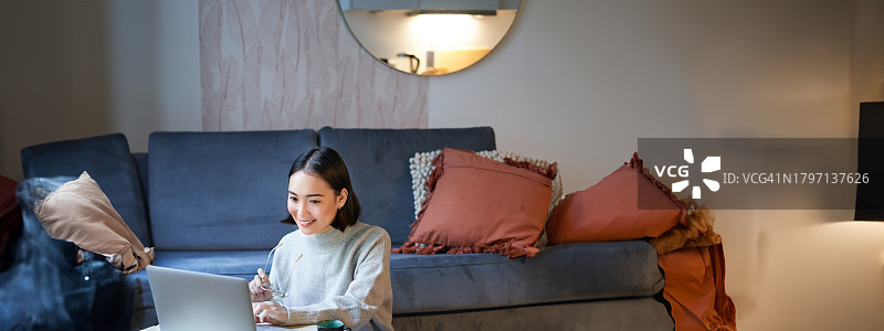 竖版在家坐在地板上用笔记本电脑工作的女人照片图片素材