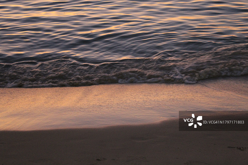 仰视日落时海滩上的金色海浪图片素材