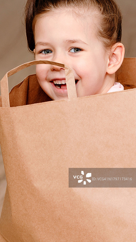 小女孩坐在棕色纸质购物袋里图片素材