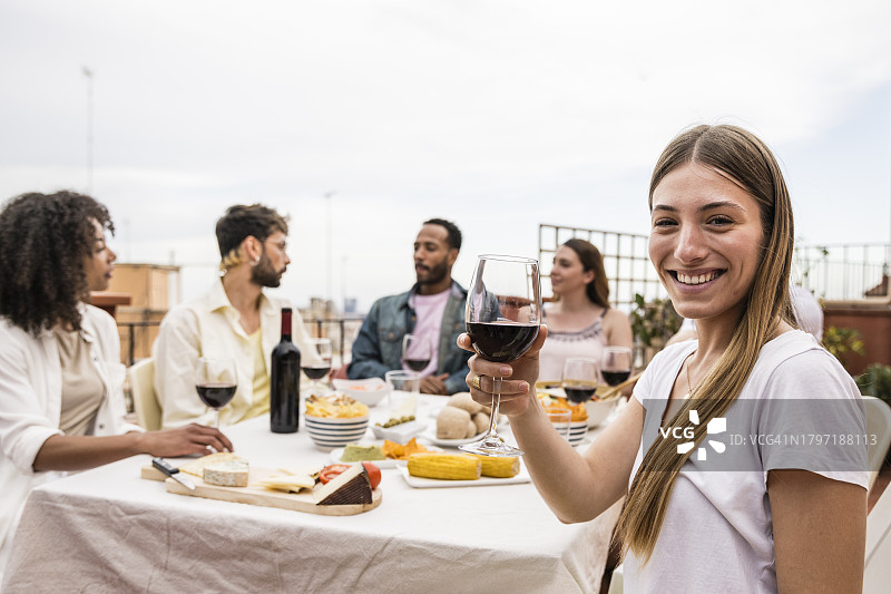 快乐的年轻女人在聚会上拿着一杯酒看着镜头图片素材