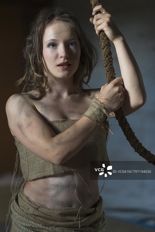 靠墙站立手持绳索的年轻女人肖像图片素材