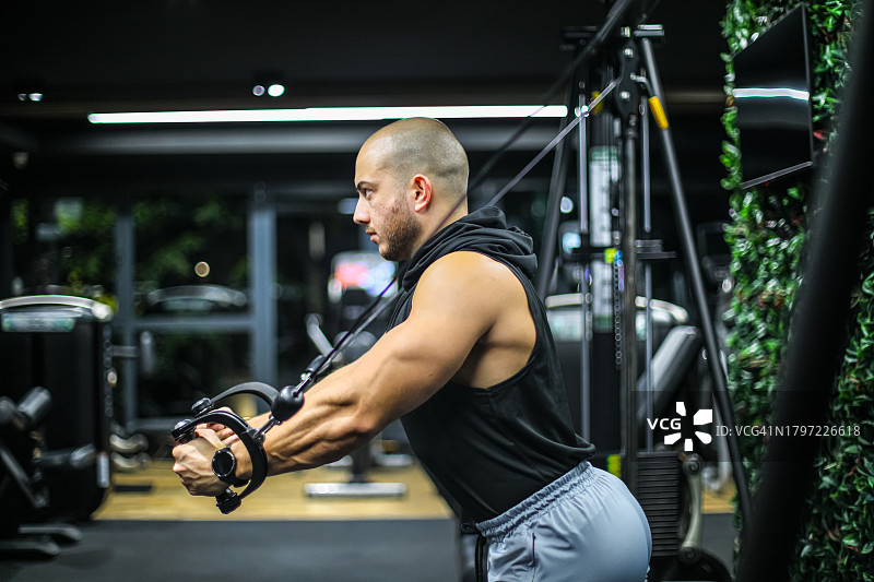 在健身房用滑轮器械锻炼的男人图片素材