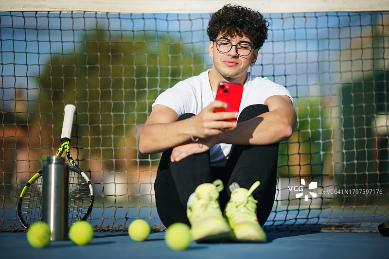 在球场休息时使用手机的网球运动员图片素材