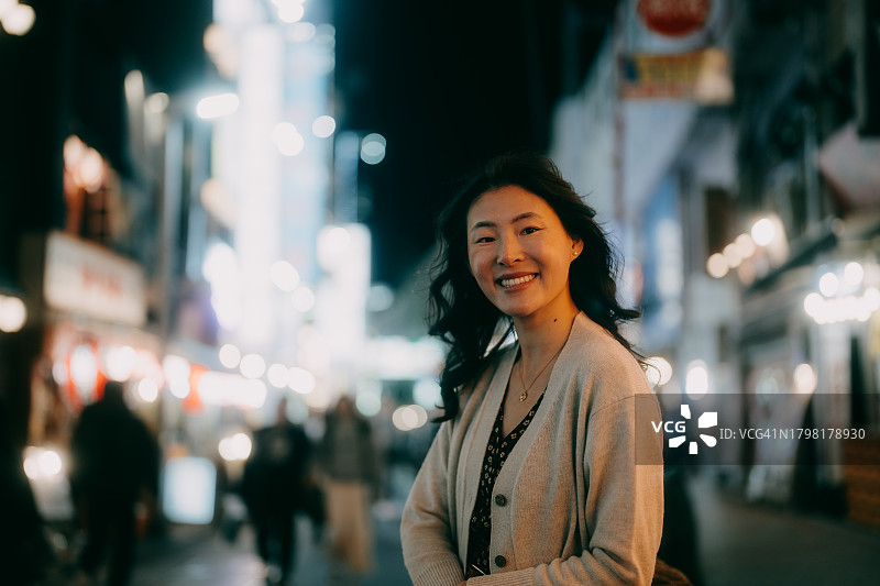 夜晚东京街头对着镜头微笑的女人图片素材
